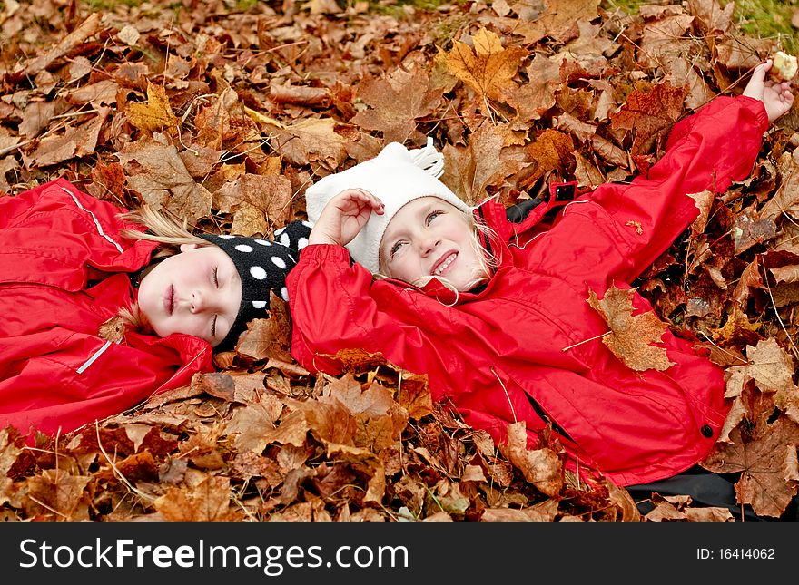 Children lying in heap of autumn leaves. Children lying in heap of autumn leaves.