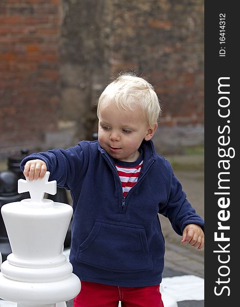 Cute blond toddler boy playing giant chess. Cute blond toddler boy playing giant chess