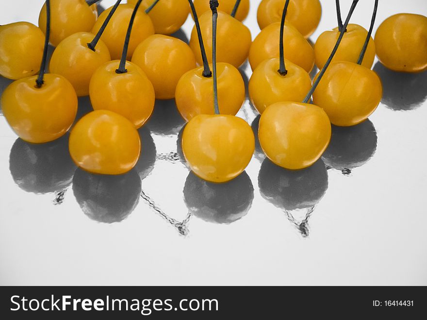 Yellow cherries with black and white reflection, selective coloring photo still life