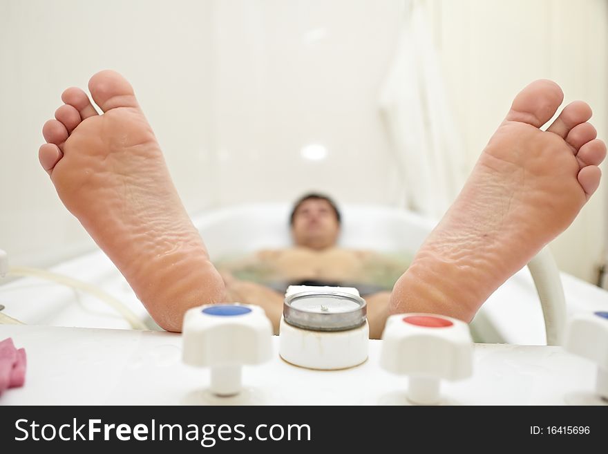 Heels lying person in the bath on the procedures