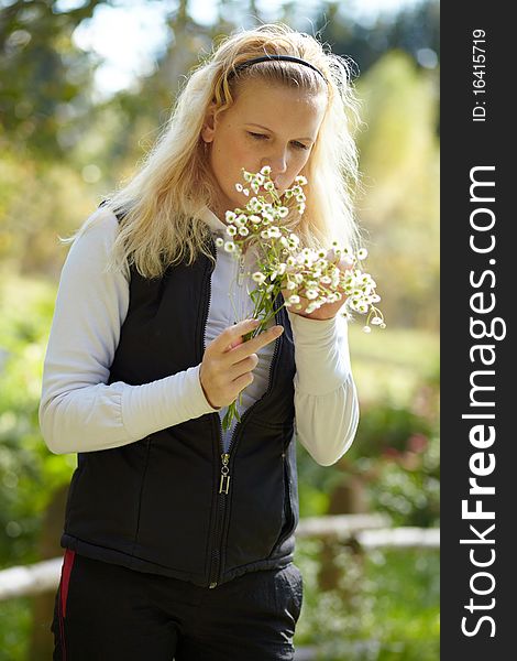 Young blonde girl with a bouquet of daisies in autumn