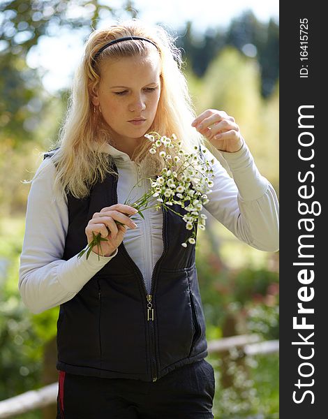 Blonde girl looks at the bouquet of daisies