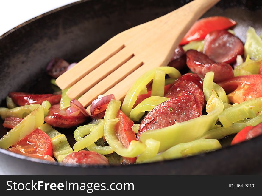 Preparing a dish of stewed vegetables and sausage. Preparing a dish of stewed vegetables and sausage