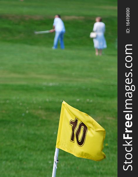 Out of focus golfers with yellow flag. Out of focus golfers with yellow flag