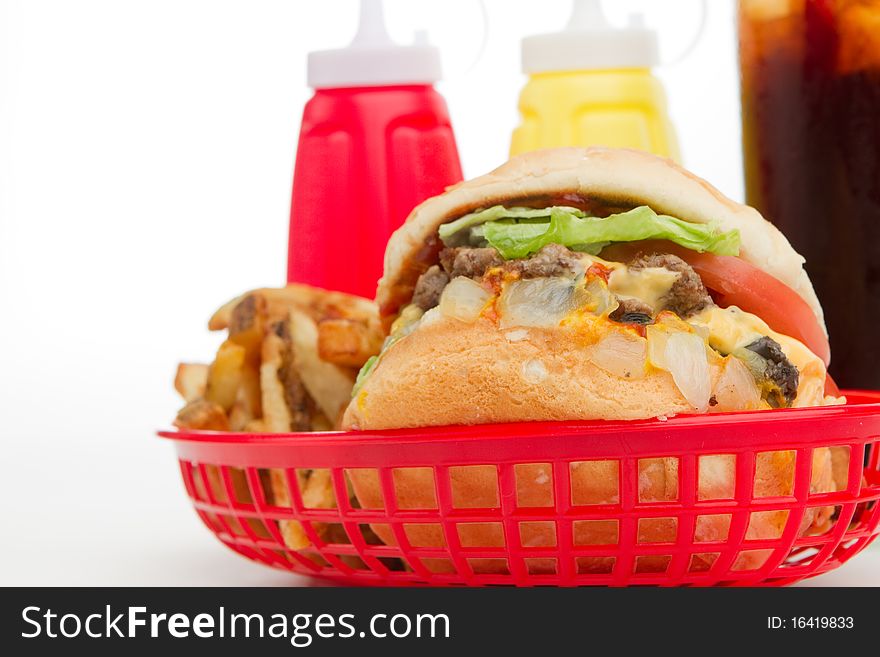 An American lunch consisting of burger, french fries, condiments and soft drink.