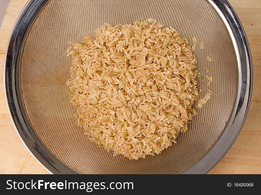 Brown rice washed in a wired strainer. Brown rice washed in a wired strainer.