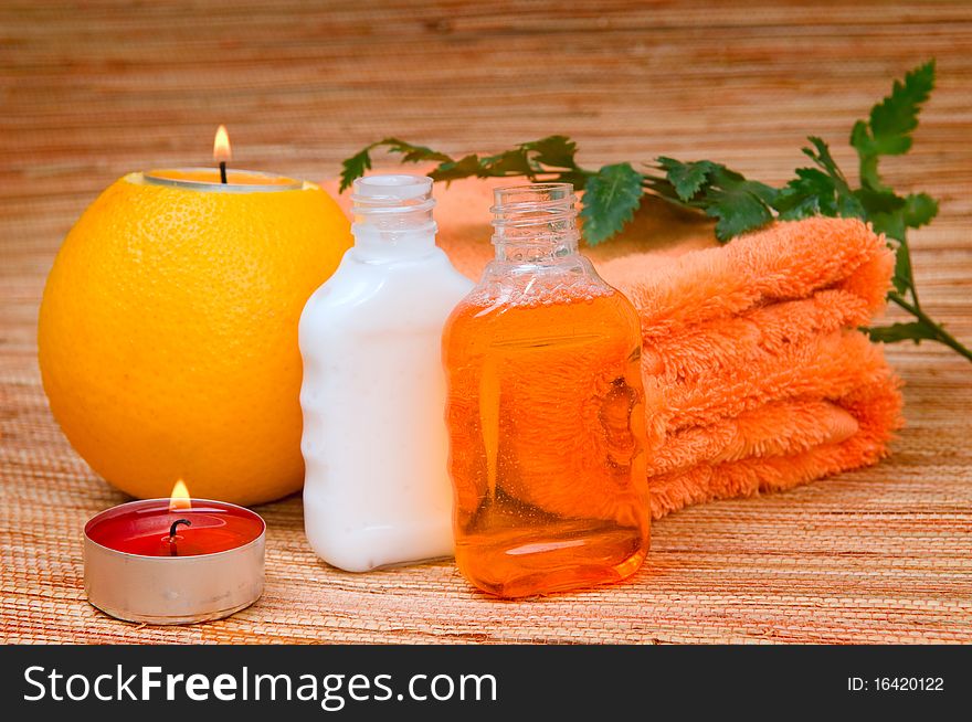 Orange towel, Fern branch and a burning candle in citrus. Orange towel, Fern branch and a burning candle in citrus
