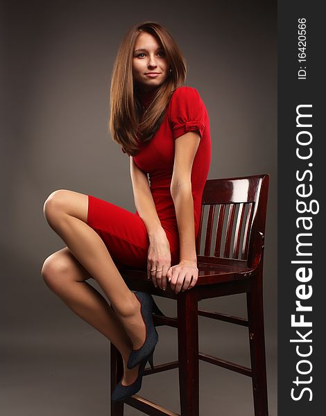 Pretty smiling girl in a red dress on the chair. Pretty smiling girl in a red dress on the chair