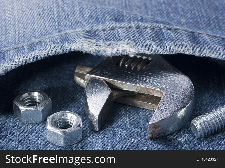 Wrench with bolts and nuts against a pocket of jeans.