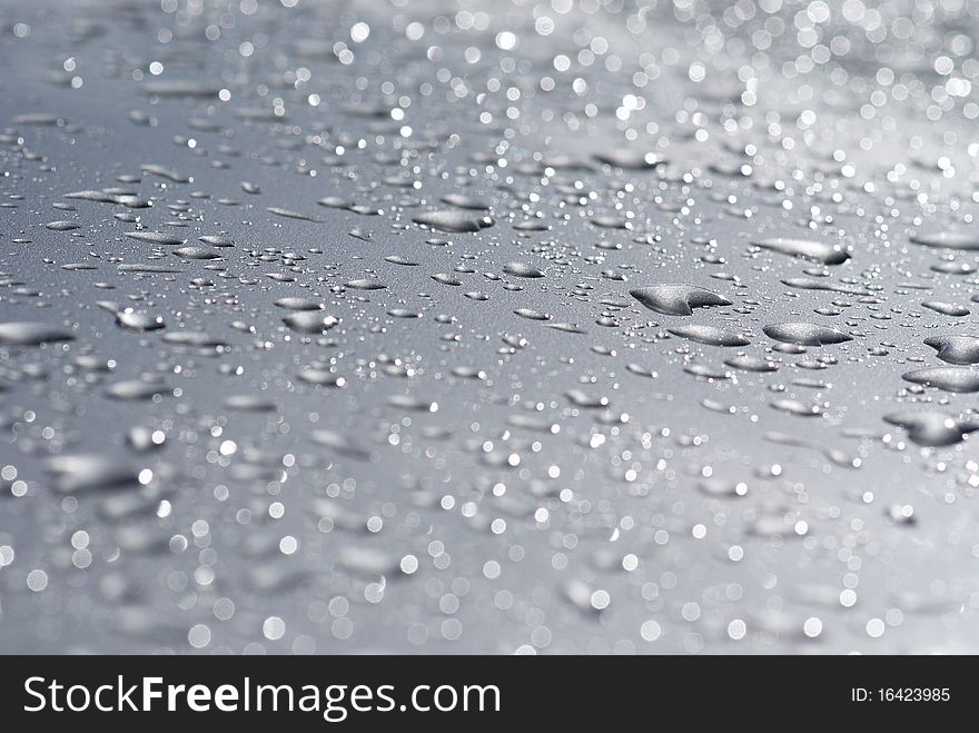 Raindrops on the hood of a gray car