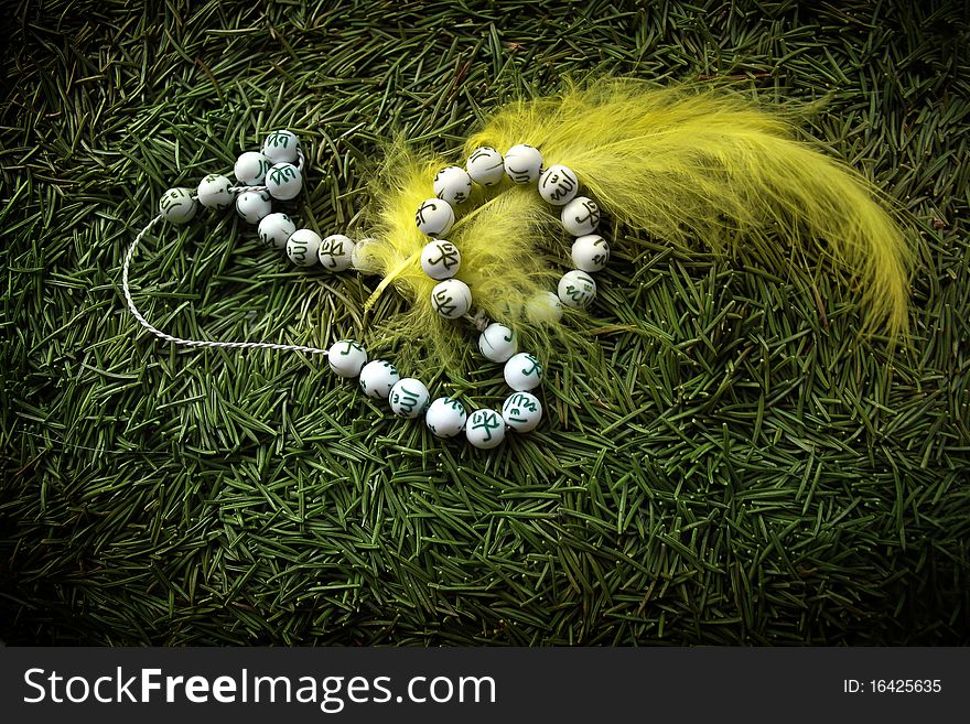 Beads and yellow feather against green needles