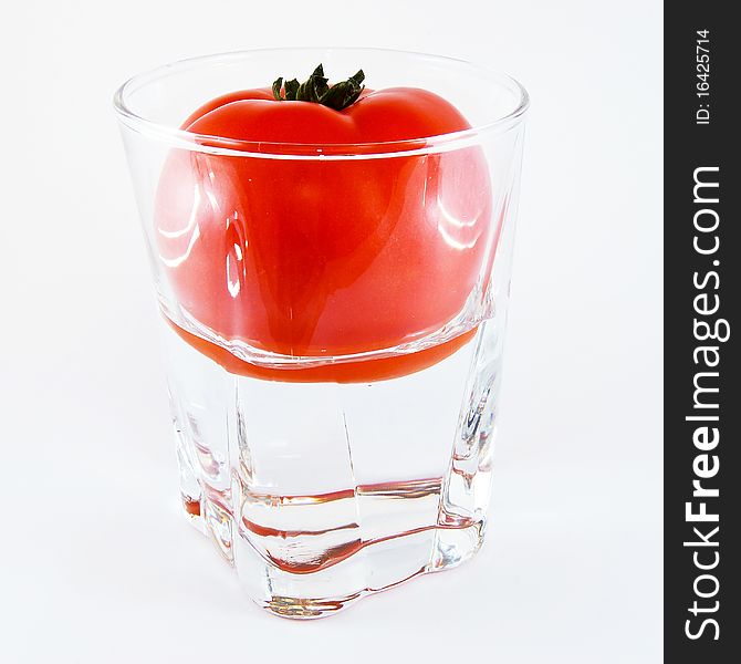 Tomato in a glass of water isolated on white background