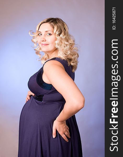 Photo of expectant mother in a dark blue dress in a studio