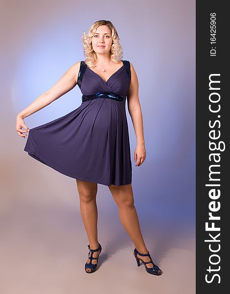 Photo of expectant mother in a dark blue dress in a studio