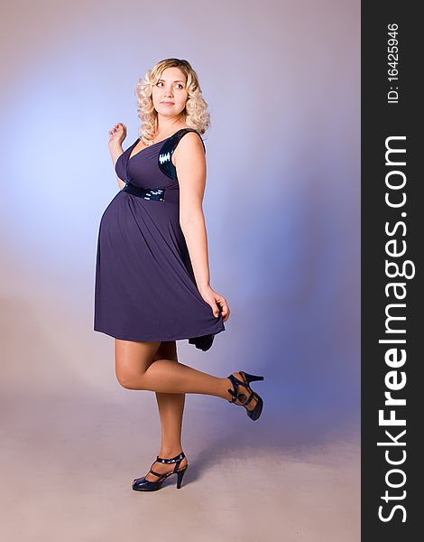 Photo of expectant mother in a dark blue dress in a studio