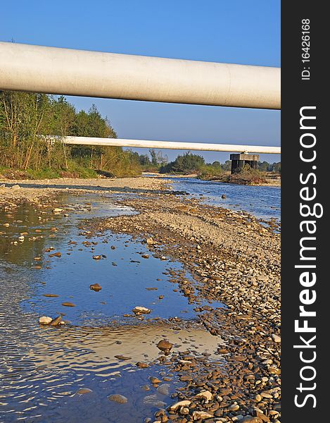 Transition of two pipelines of a high pressure through mountain small river in a summer landscape. Transition of two pipelines of a high pressure through mountain small river in a summer landscape