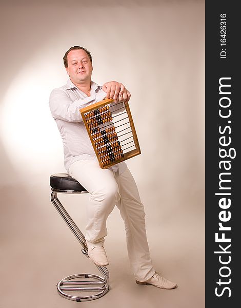 Man sits on a high chair with abacus in hands