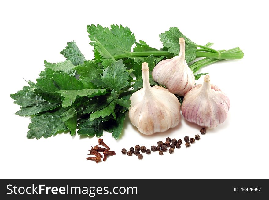 Garlic with leaves of a celery and spices is isolated on a white background