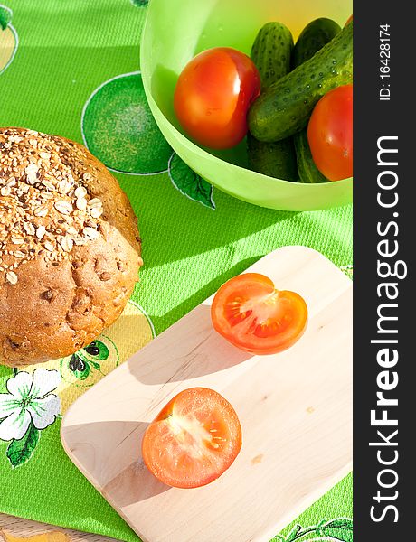 Bread, vegetables on the cutting board over the green colorful napkin. Bread, vegetables on the cutting board over the green colorful napkin