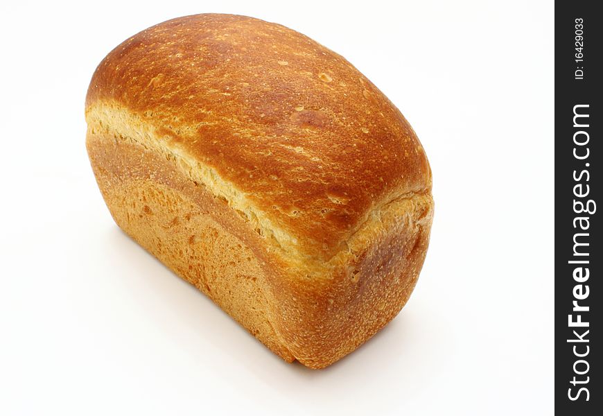 The ruddy long loaf of bread with the fried crust is isolated on a white background