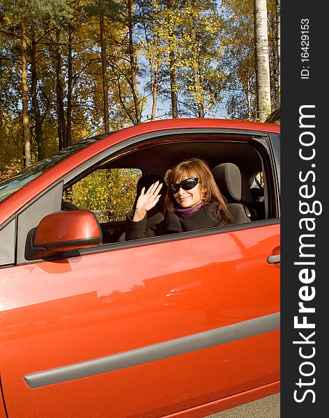 The girl in the red car in an autumn sunny day