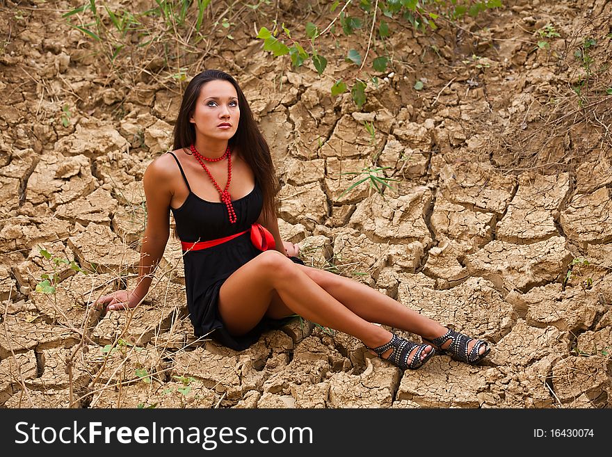 Confused girl sitting on a dried soil. Confused girl sitting on a dried soil