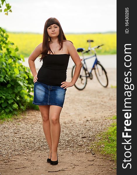 Young, beautiful girl in short skirt at summer day with bicycle at the background. Young, beautiful girl in short skirt at summer day with bicycle at the background.