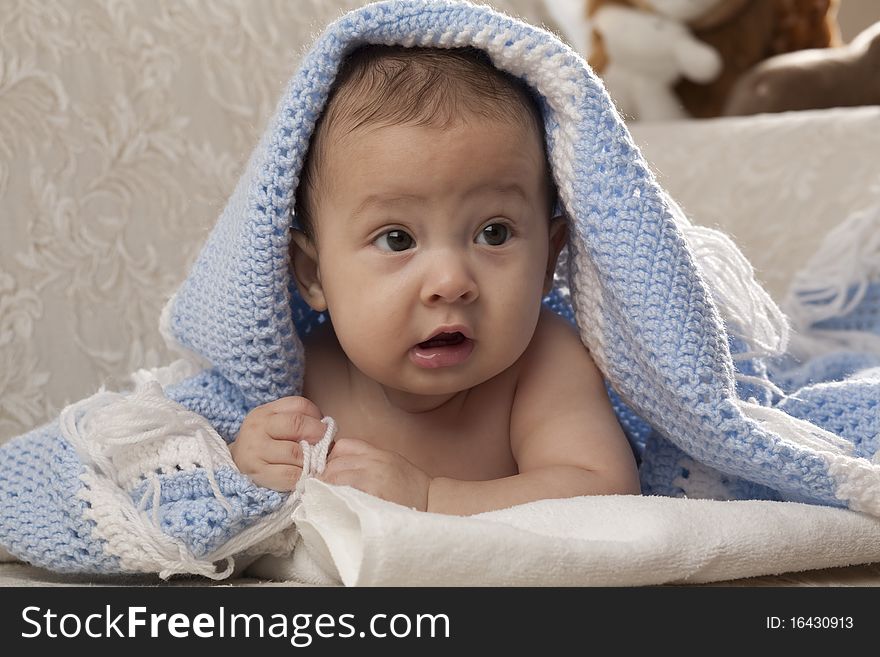 Horizontal image of a cute baby under a blue blanket
