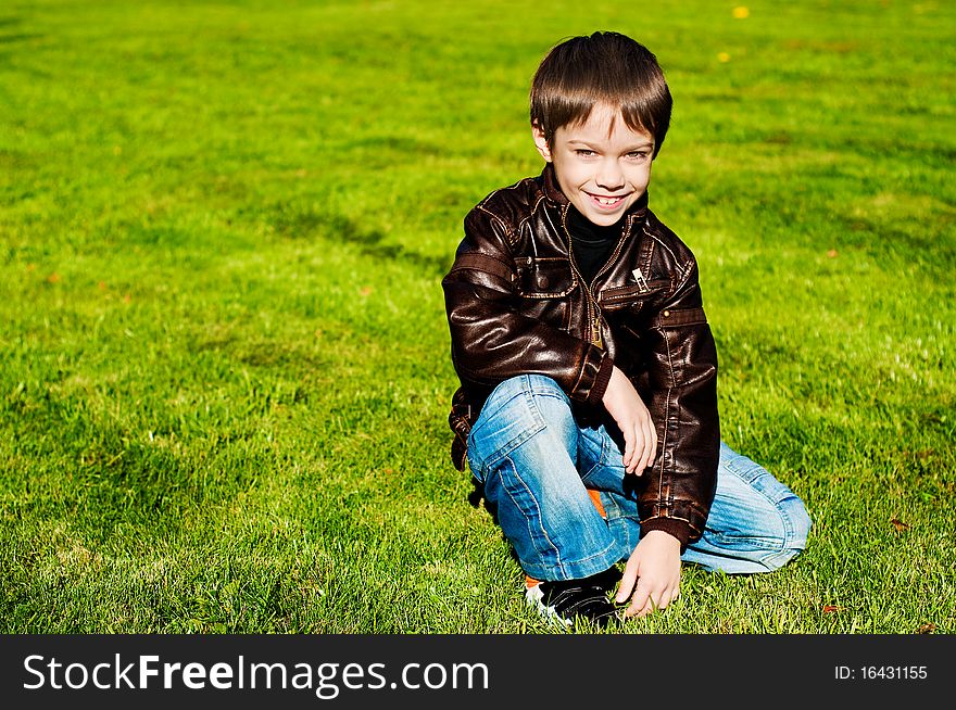 Little 7 year boy Lying Down on the green grass and smiling. Little 7 year boy Lying Down on the green grass and smiling