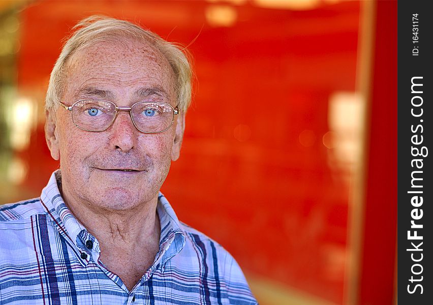 Portrait of a retired old man smiling against red background