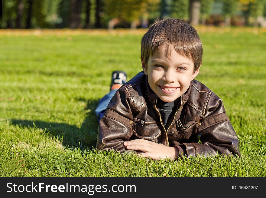 Little 7 year boy Lying Down on the green grass and smiling. Little 7 year boy Lying Down on the green grass and smiling