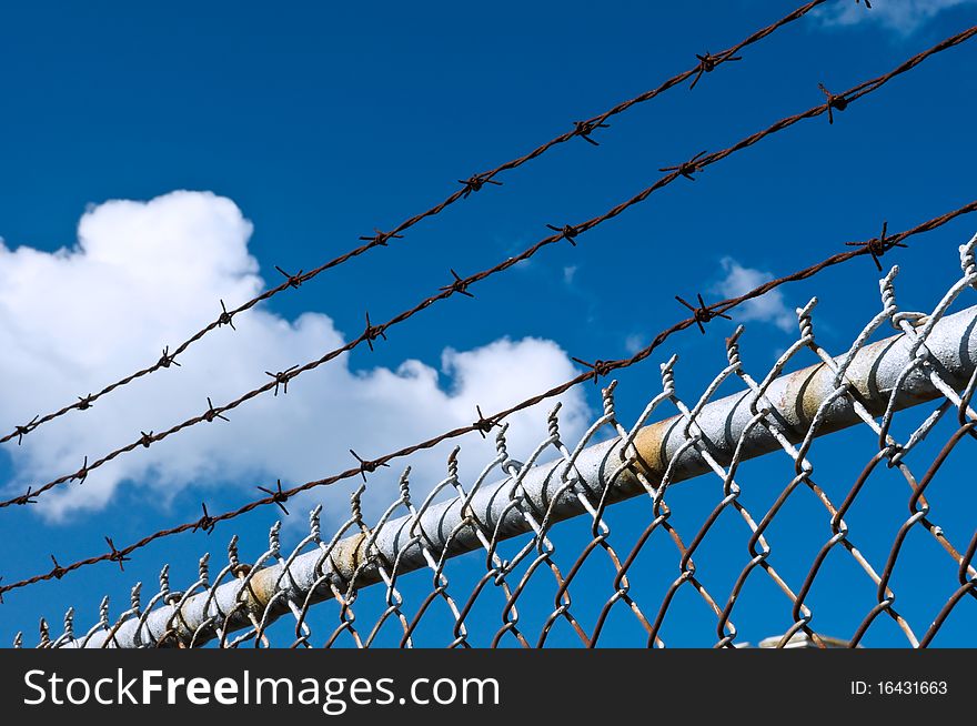 Barbed wire and fence on sky background