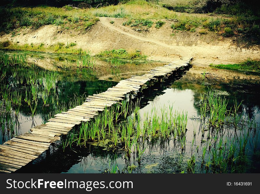 Narrow old wooden bridge across the small river