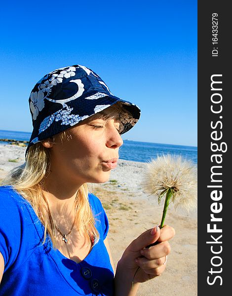 Beautiful mature woman blowing dandelion seeds