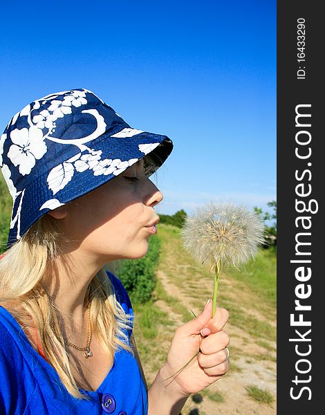 Beautiful mature woman blowing dandelion seeds