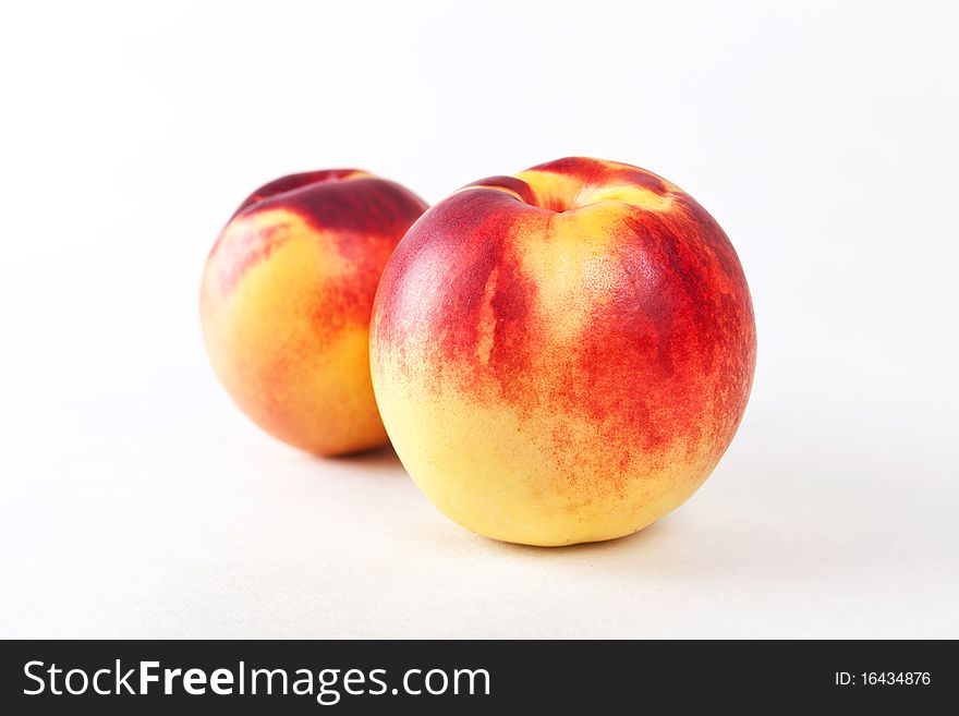 Two sweet ripe nectarines isolated on white. Studio shot