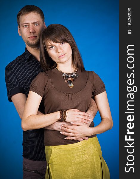 Portrait of a happy young couple hugging each other against blue background