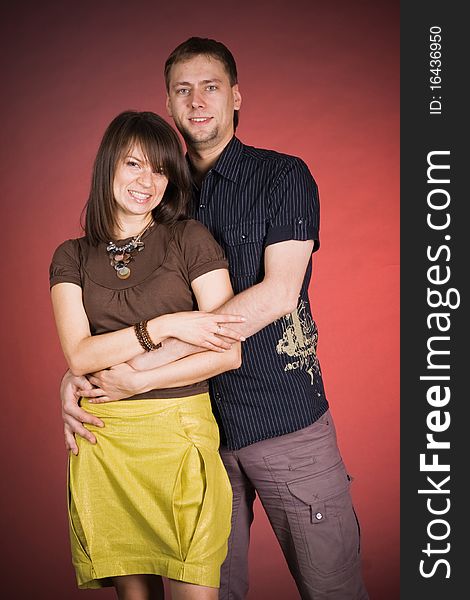 Portrait of a happy young couple hugging each other against red background