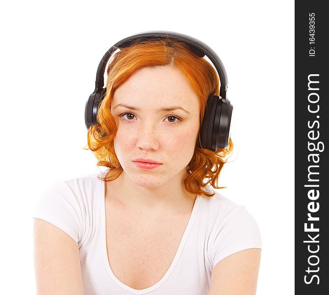 Redhead girl listening music in headphones isolated on white