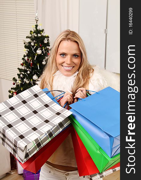 Beautiful blond female angel holding some shopping bags in front of a christmas-tree. Beautiful blond female angel holding some shopping bags in front of a christmas-tree