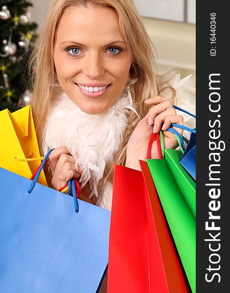 Beautiful blond female angel holding some shopping bags in front of a christmas-tree. Beautiful blond female angel holding some shopping bags in front of a christmas-tree