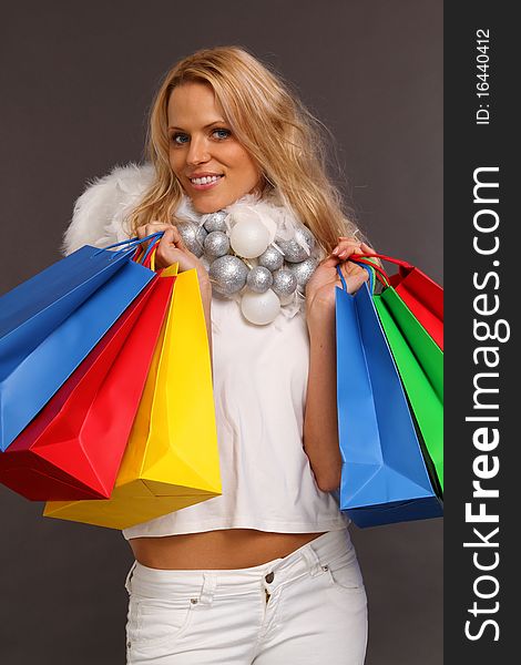 Beautiful blond female angel holding some colored shopping bags. Beautiful blond female angel holding some colored shopping bags