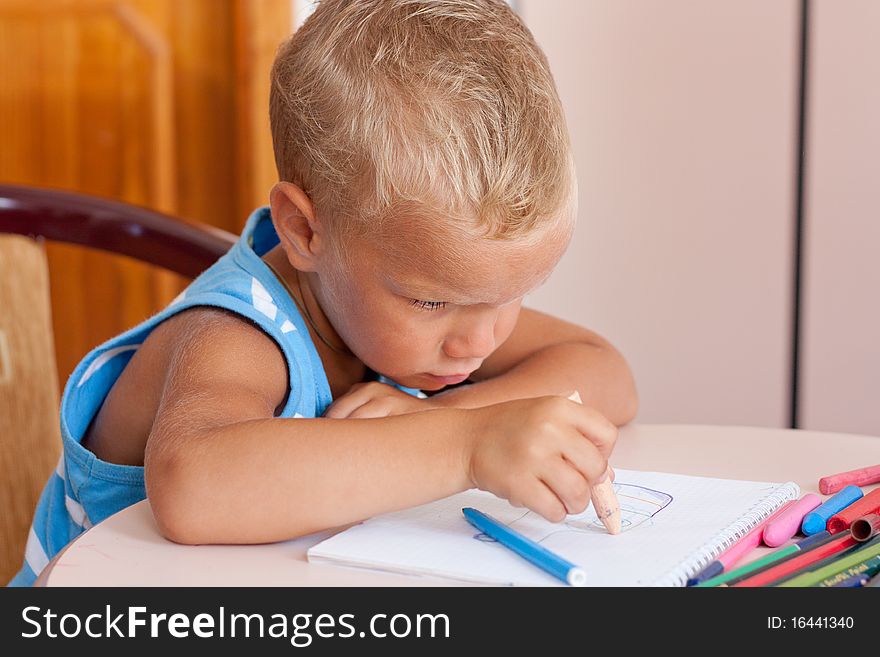 Little boy crayons at desk