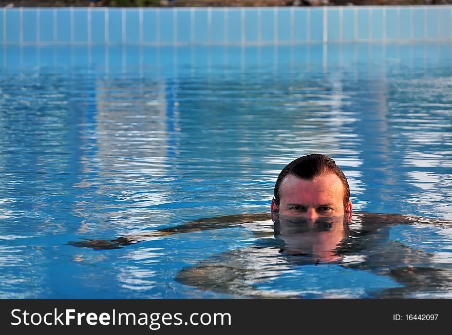 Man swimming in swimming pool. Summer time.