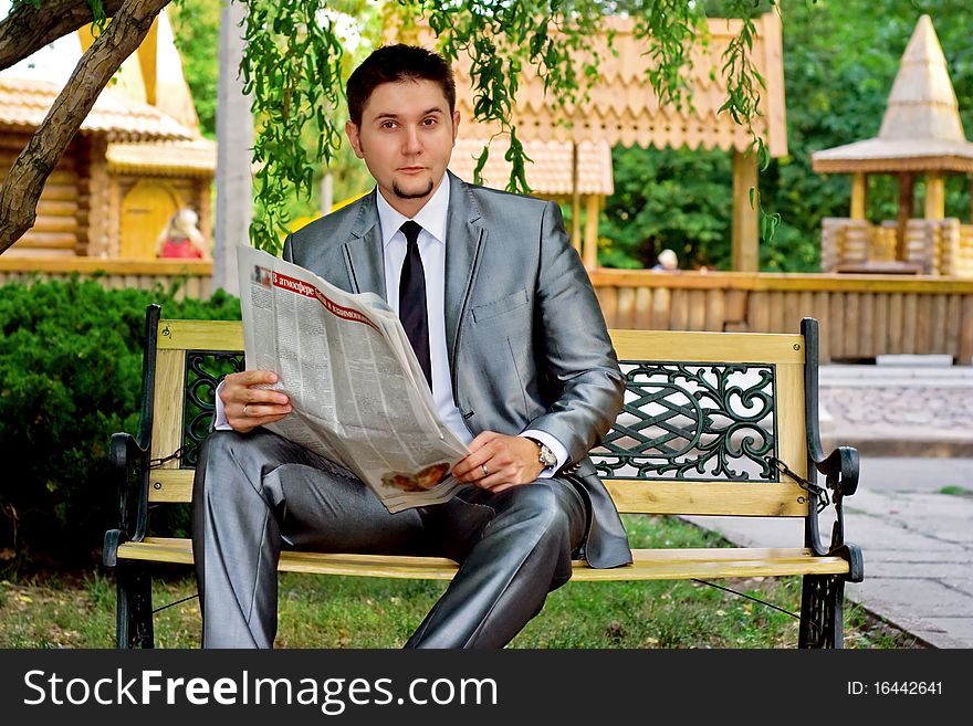 Young businessman reading a newspaper in the park