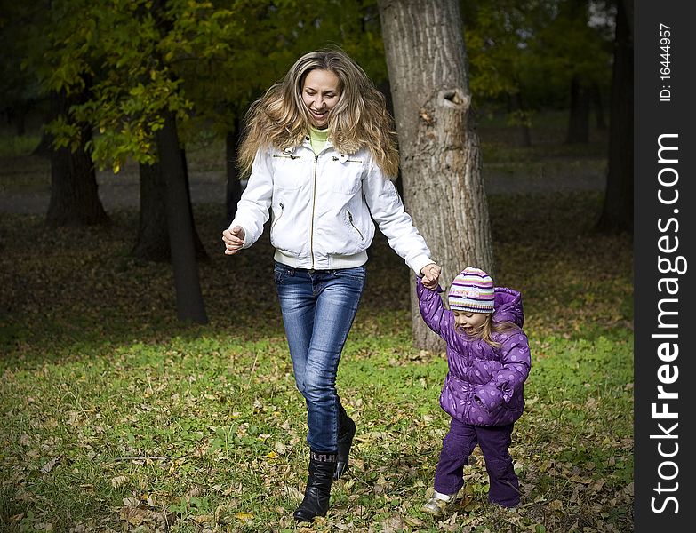 Mom and daughter running in the autumn park. Mom and daughter running in the autumn park