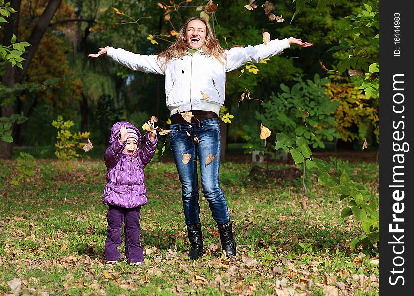 Mother And Daughter Throwing Dry Leaves In Autumn