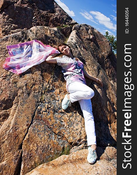 Positive young girl against the rock in summer