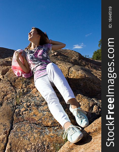 Positive young girl against the rock in summer