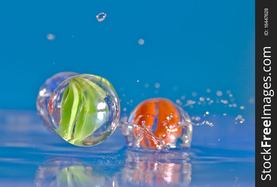 Marbles falling into blue water